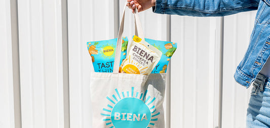 Person holding a bag filled with Biena Snacks.