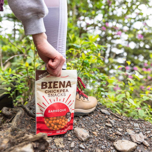 Bag of Biena Barbecue Chickpea Snacks being picked up in the forest