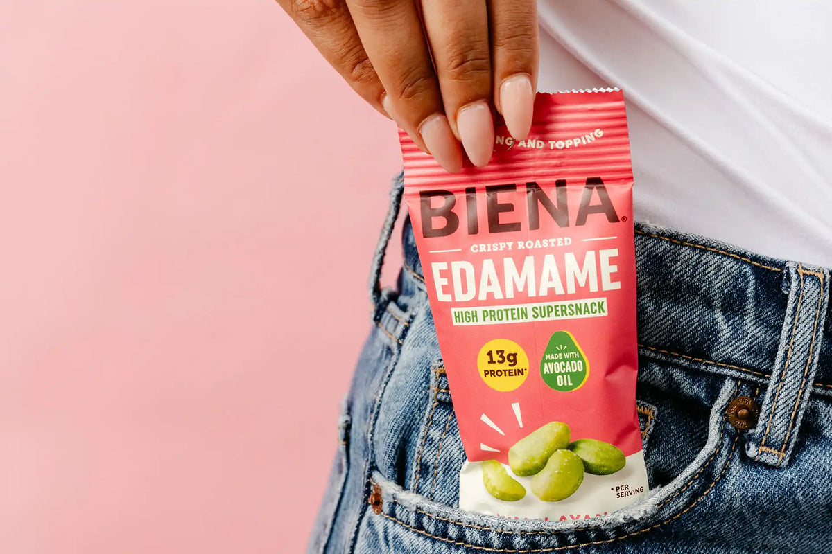 Hand pulling out package of Biena Crispy Roasted Edamame Supersnakcs out of a jeans pocket